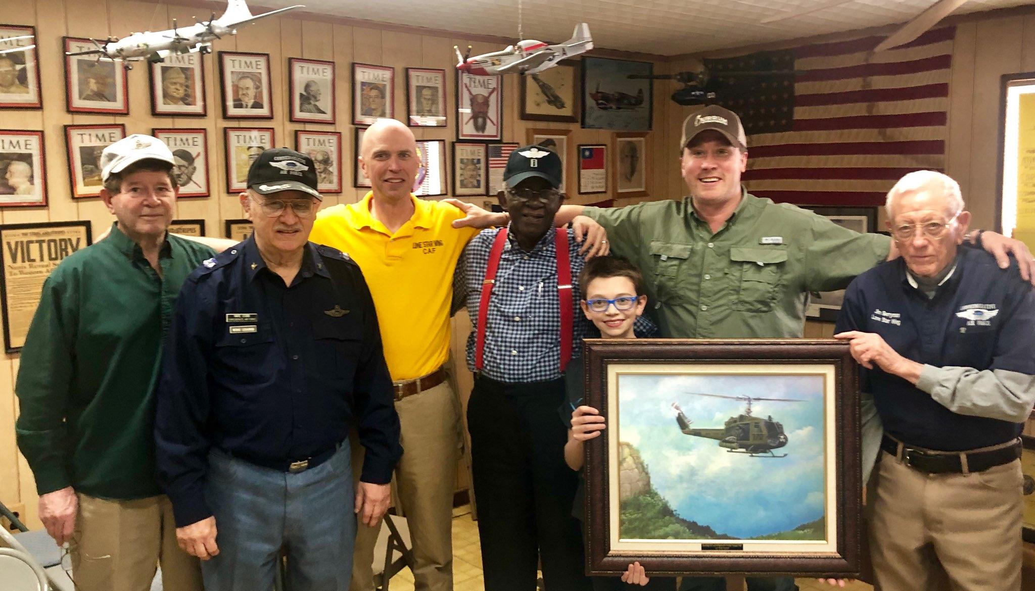 Photo of some of the members of the Lone Star Wing of the Commemorative Air Force.  Left to Right: Doyle Curry, Mike Cobb, Jimmy Page, Bob Snead, Wilson Page, Travis Keeney, and Jim Berryman.  Pictured with an original artwork donated by Bob of his UH-1C gunship 136, entitled 